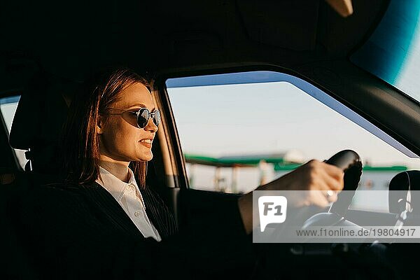 Junge schöne stilvolle Mädchen Fahrer in einer Jacke und Sonnenbrille fahren ein Auto  Geschäftsreise