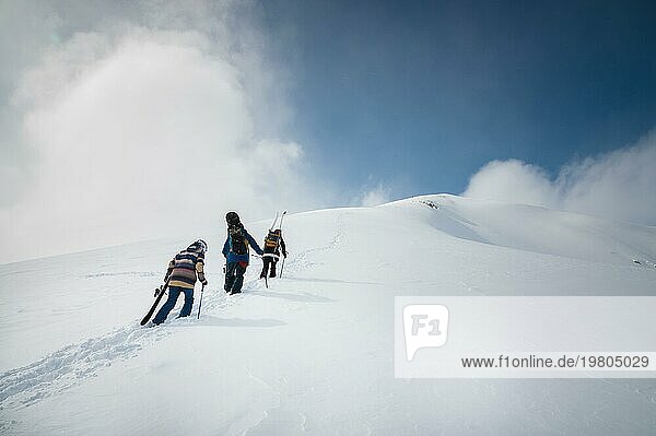 Snowboarder und Skifahrer fahren mit Ausrüstung bergauf. Skifahren abseits der Piste  Freeride an einem sonnigen Tag