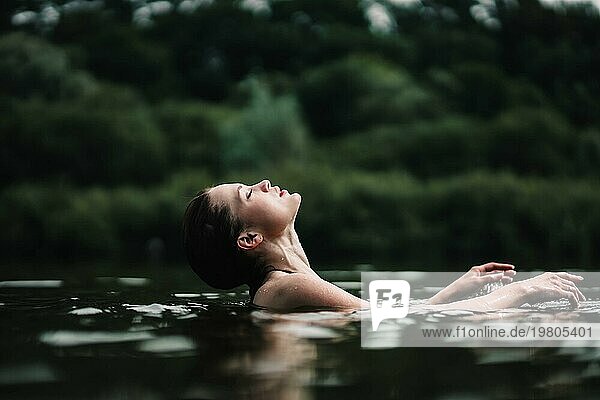 Ein junges  schlankes  schönes und heißes Mädchen mit nassen Haaren schwimmt im See  reist zu Wasserfällen  entspannt sich am See