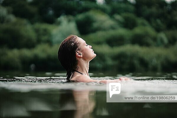 Ein junges  schlankes  schönes und heißes Mädchen mit nassen Haaren und großen Lippen schwimmt im See  reist zu Wasserfällen  entspannt sich am See