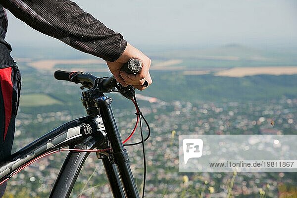 Nahaufnahme der Hand eines Fahrers am Lenker eines Mountainbikes mit geringer Tiefenschärfe vor dem Hintergrund der Stadt
