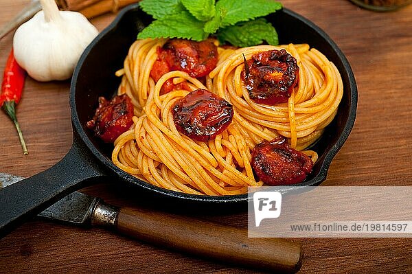 Italienische Spaghetti und Tomaten mit Minzblättern auf Eisenpfanne über Holzbrett  Food photography  Food photography  Food photography