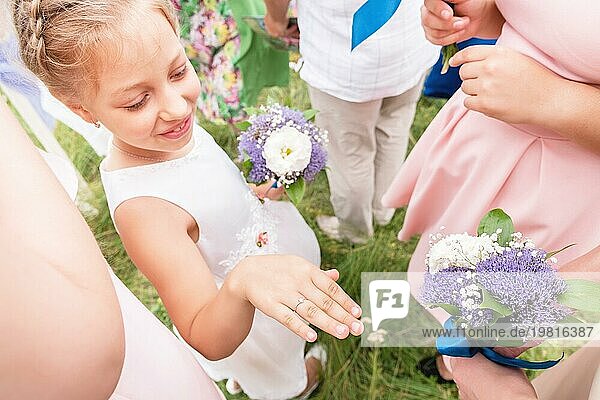 Kleine süße Freundin der Braut prahlt mit ihren Ringen vor erwachsenen Freundinnen bei der Ausgangsanmeldung