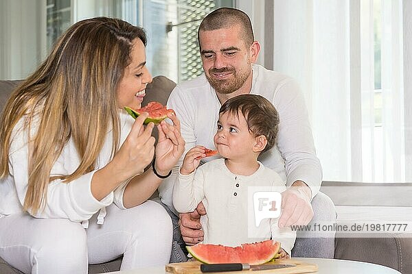 Neue Erfahrungen für einen kleinen Jungen  der mit seinen Eltern im Wohnzimmer eine Wassermelone probiert