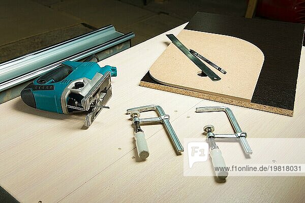 Vorbereitetes Werkzeug Stichsäge mit Holzklammern und einem Bleistift mit Lineal auf dem Tisch des Zimmermanns