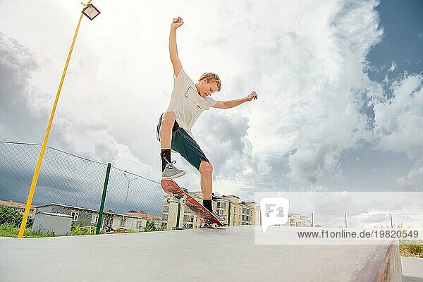Junge Skateboarder in einem Skatepark  der einen manuellen Trick auf einem Skateboard vor einem Himmel und Gewitterwolken ausführt