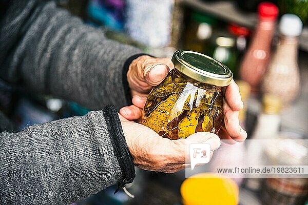 Alte faltige Hände halten ein Glas mit Bergmarmelade aus den Blättern der kaukasischen Bäume in den Bergen