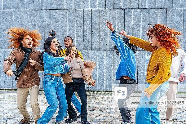 Fröhliche multiethnische Freunde tanzen aufgeregt in der Stadt zusammen