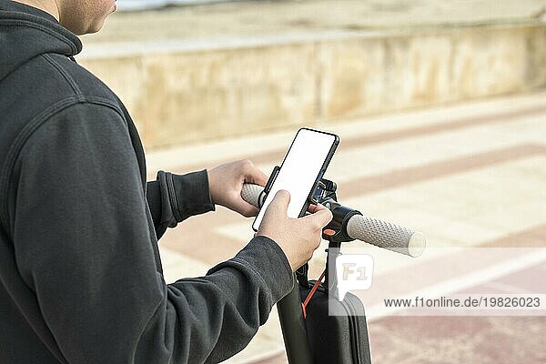 Draufsicht 14 20 Jahre alt  Rollerfahren mit Handy Navigationsroute draußen in der Natur  E Mobility Urban Leisure Concept