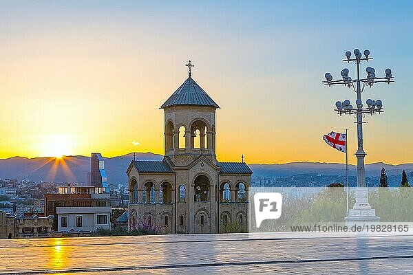 Glockenturm der Dreifaltigkeitskirche oder Tsminda Sameba Kathedrale Sonnenuntergangspanorama und georgische Flagge in Tiflis  Georgien  Asien