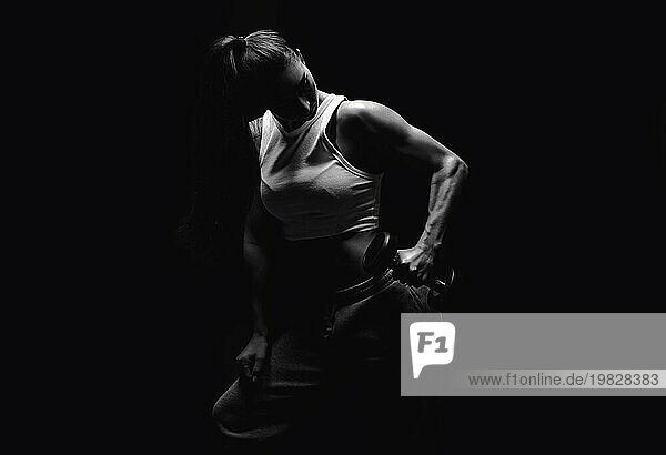 Sportliche Fitnessfrau die im Studio vor einem dunklen Hintergrund posiert. Foto einer attraktiven Frau in modischer Sportkleidung. Sport und gesunder Lebensstil. Gemischte Medien