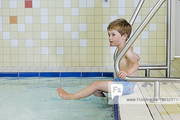 Topic: Preschool child sitting on the edge of the pool in a public bath