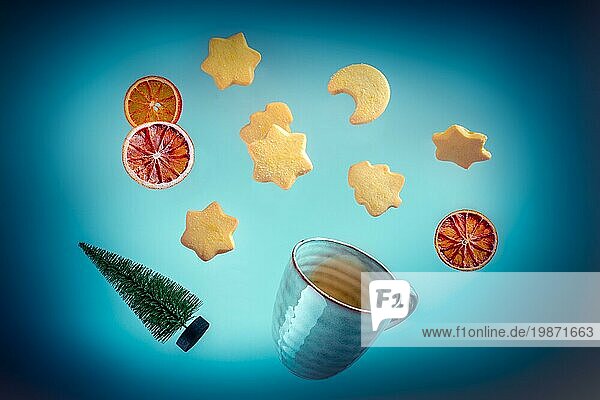 Fliegende Butterkekse  Tee und ein Weihnachtsbaum auf einem dunkelblauen Hintergrund. Ein kreativer Entwurf für eine Weihnachtsgrußkarte oder eine Einladung