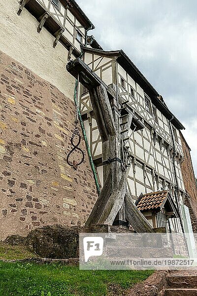 Teil der Außenmauer der Wartburg bei Eisenach mit Fachwerkbauten und historischem Baukran