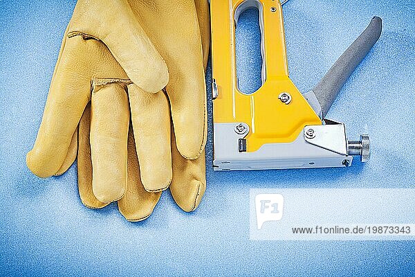 Leder Arbeitshandschuhe gelbe Konstruktion Heftklammer auf blauem Hintergrund Draufsicht