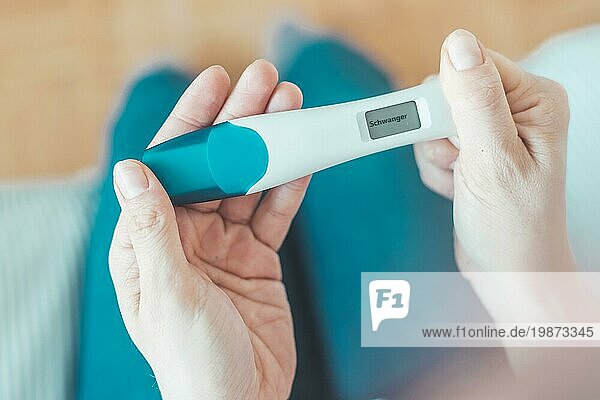 Frau hält Schwangerschaftstest in der Hand  Ergebnis ist schwanger  ?Schwanger?