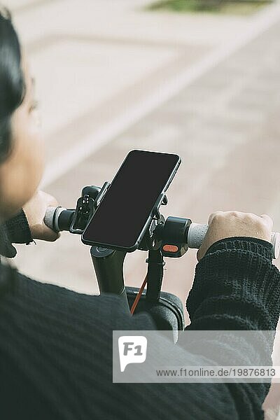 Blick über die Schulter auf eine Frau auf einem Fahrrad  die ein am Lenker befestigtes Smartphone benutzt