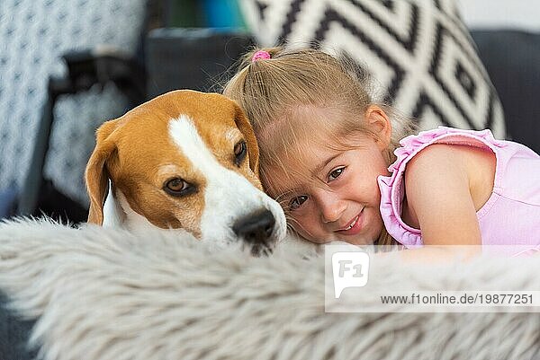 Kind kuschelt mit einem Hund auf dem Sofa im Hinterhof. Glückliche Kindheit mit Beagle Haustier