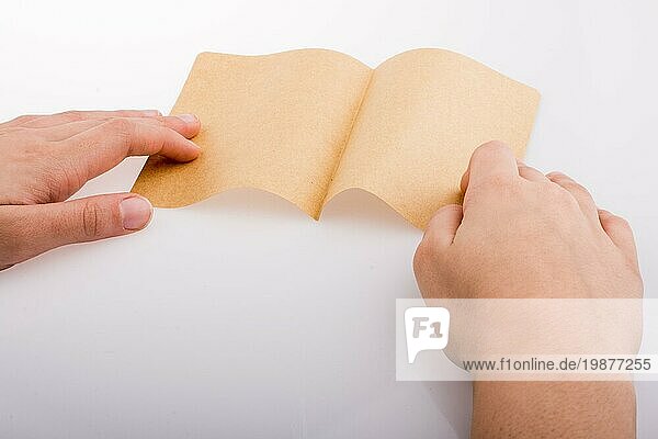 Hand hält ein Blatt Papier auf einem weißen Hintergrund