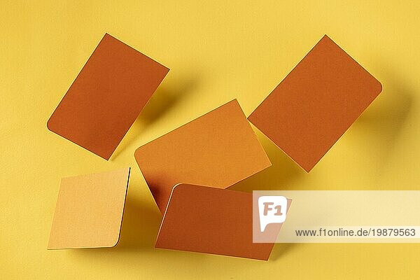 Dicke orangefarbene Visitenkarten mit einer abgerundeten Ecke  die auf einem gelben Papierhintergrund schweben  ein Mockup für eine kreative Designpräsentation