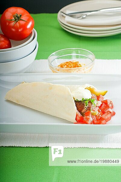 Frischer traditioneller Falafel Wrap auf Fladenbrot mit frischen gehackten Tomaten  Food photography