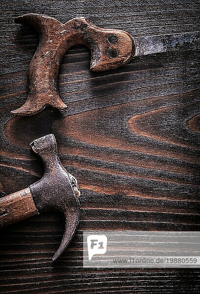 Rusty antiken Handsäge mit Klaue Hammer auf Vintage dunklen hölzernen Hintergrund Konstruktion Konzept