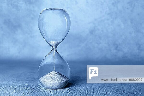 Konzept Die Zeit läuft ab . Eine Sanduhr mit durchfallendem Sand  mit Kopierraum  getönt in der Farbe des Jahres  blau
