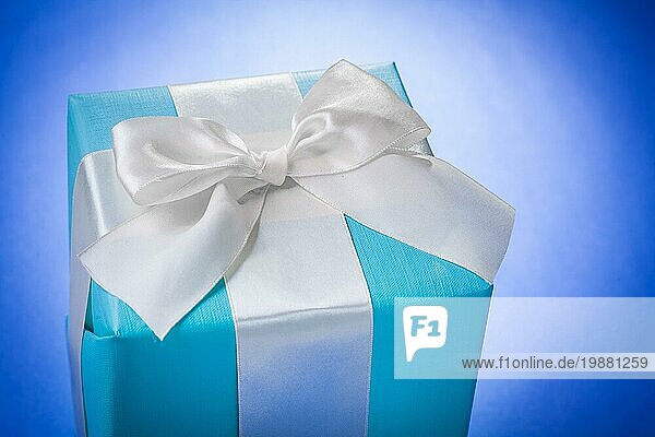 Blaue Geschenkbox mit weißer Schleife auf blauem Hintergrund