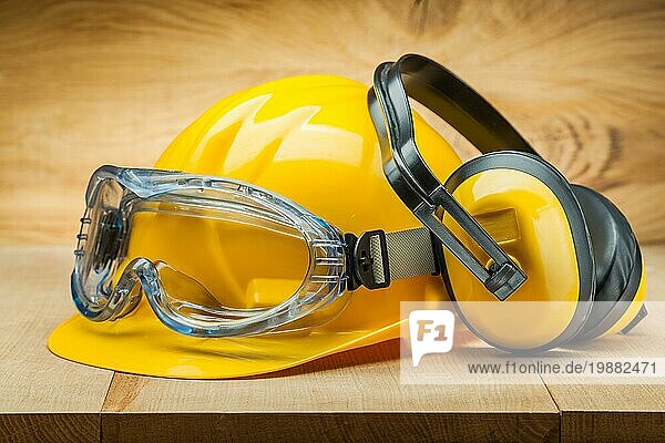 Sicherheit der Arbeit. Bau Sicherheit Werkzeuge. gelben Helm blaue Schutzbrille und Kopfhörer auf Holz Hintergrund