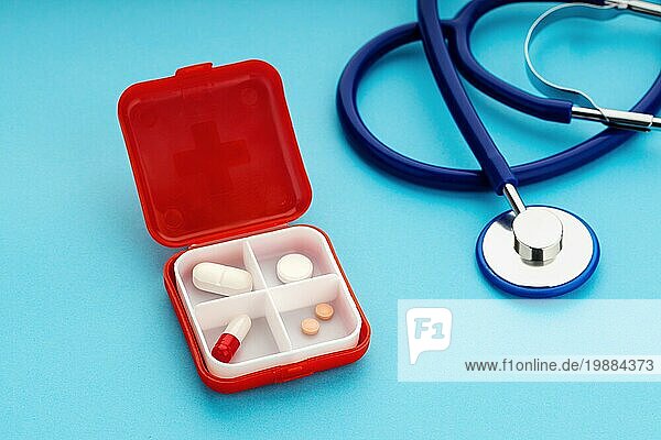 Daily Pill Box und Stethoskop auf blauem Hintergrund. Medizin  Gesundheitswesen und Apotheke Konzept