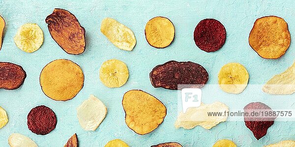 Eine Panoramaaufnahme von trockenem Obst und Gemüse Chips. Gesunder veganer Snack  ein Bio Lebensmittel Flachbettmuster auf einem blaugrünen Hintergrund