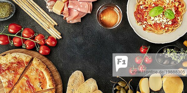 Italienisches Essen Panorama mit Copy Space. Pizza  Pasta  Käse  Schinken  Wein  Oliven  Pesto  Kapern  Aufnahme von oben  die einen Rahmen mit Platz für Text bildet  eine Flatlay Designvorlage auf schwarzem Hintergrund