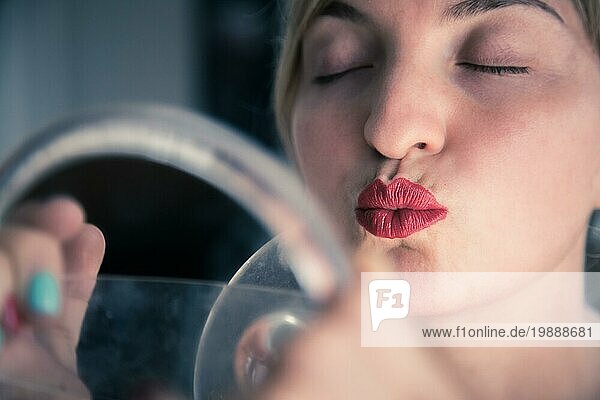 Hübsche weiße Frau mit roten sinnlichen Lippenstift und bunten Nagellack ist in den Spiegel schauen  Kussmund
