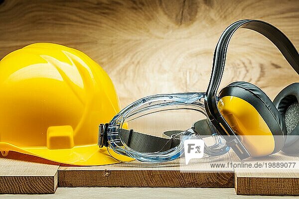 Sicherheitswerkzeuge. blaue Schutzbrille gelber Helm und Kopfhörer auf Holz Hintergrund
