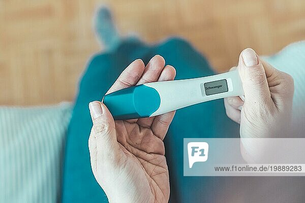 Frau mittleren Alters hält einen Schwangerschaftstest in der Hand  das Ergebnis ist schwanger  ?Schwanger?