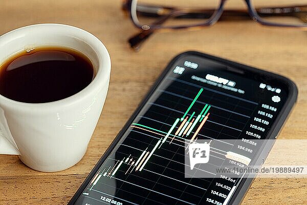 Börsenhandel auf tragbarem Gerät Konzept. Chart auf Smartphonebildschirm auf dem Schreibtisch. Trading oder Investment Konzept