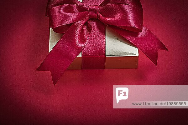 Geschenkbox mit Geschenkband auf rotem Hintergrund Urlaub Konzept