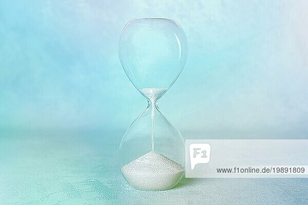 Die Zeit läuft ab Konzept. Eine Sanduhr mit Sand fällt durch  mit einem Platz für Text  in teal blau  getönten Bild