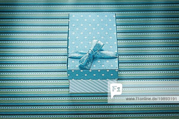Blaue Geschenkbox auf gestreifter Tischdecke Feiern Konzept