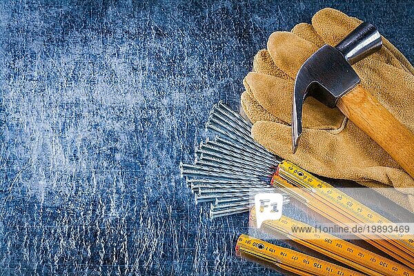 Kopieren Sie Raum Bild von Leder Arbeitshandschuhe Nägel hölzernen Messgerät und Klaue Hammer auf zerkratzt metallischen Hintergrund Baukonzept