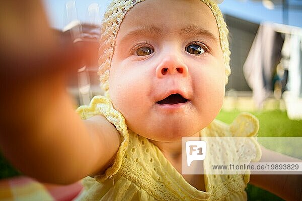 Cute Baby Mädchen in gelb erreicht Kamera in sonnigen Tag im Freien. Konzeptuell