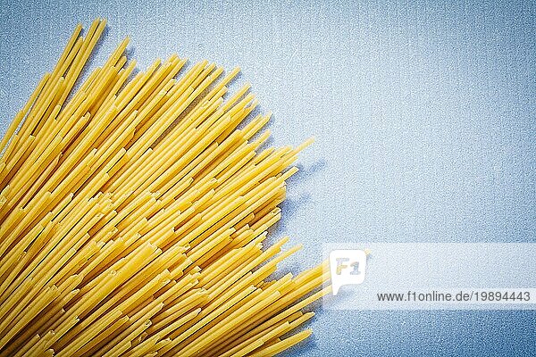 Gelbe dünne Spaghetti auf blauem Hintergrund Essen und Trinken Konzept