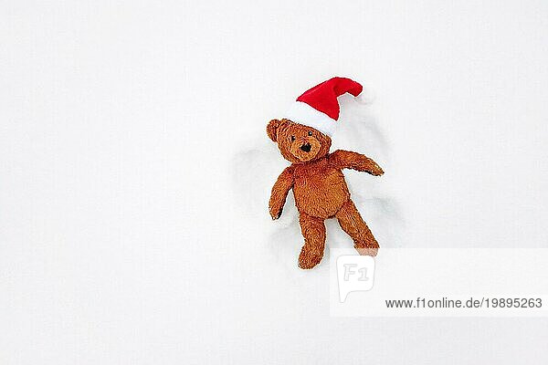 Schneeengel  Draufsicht  süßer Teddybär mit roter Weihnachtsmannmütze  der sich in den Winterferien amüsiert