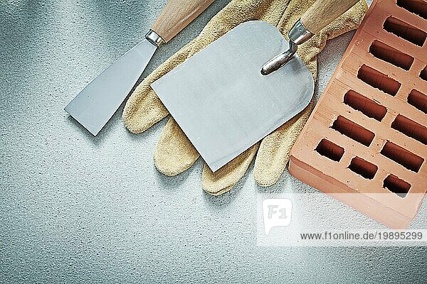 Construction Ziegel Leder Schutzhandschuhe Kitt Messer auf Betonoberfläche Maurerarbeiten Konzept