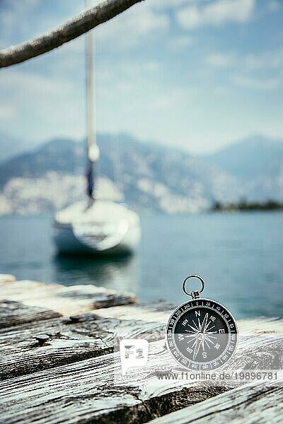 Kompass auf dem hölzernen Pier im Vordergrund  Segelboote im unscharfen Hintergrund