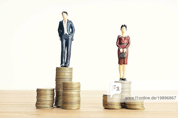 Lohnunterschied zwischen Männern und Frauen Konzept. Mann und Frau stehen oben auf dem Münzhaufen