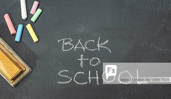 Gruppe von farbigen Kreide  Radiergummi und Hand gezeichnete Phrase Back to School auf Tafel