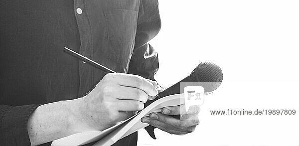 Ausschnitt eines männlichen Journalisten in einem blaün Hemd bei einer Pressekonferenz  der Notizen macht und ein Mikrofon hält
