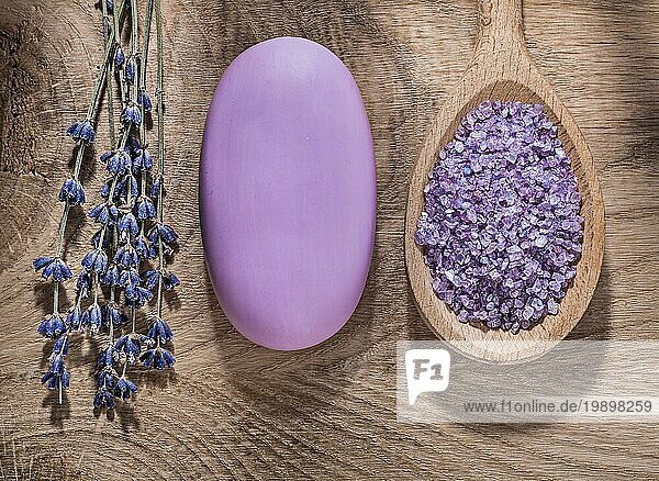 Holzlöffel mit Kristall Meersalz Bündel von Lavendel Seife auf Holzbrett Spabehandlung Konzept