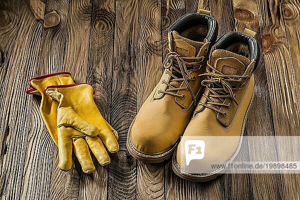 Bau Sicherheitswerkzeuge gelbe Arbeitshandschuhe und Leder Arbeitsstiefel auf Vintage Holz Hintergrund